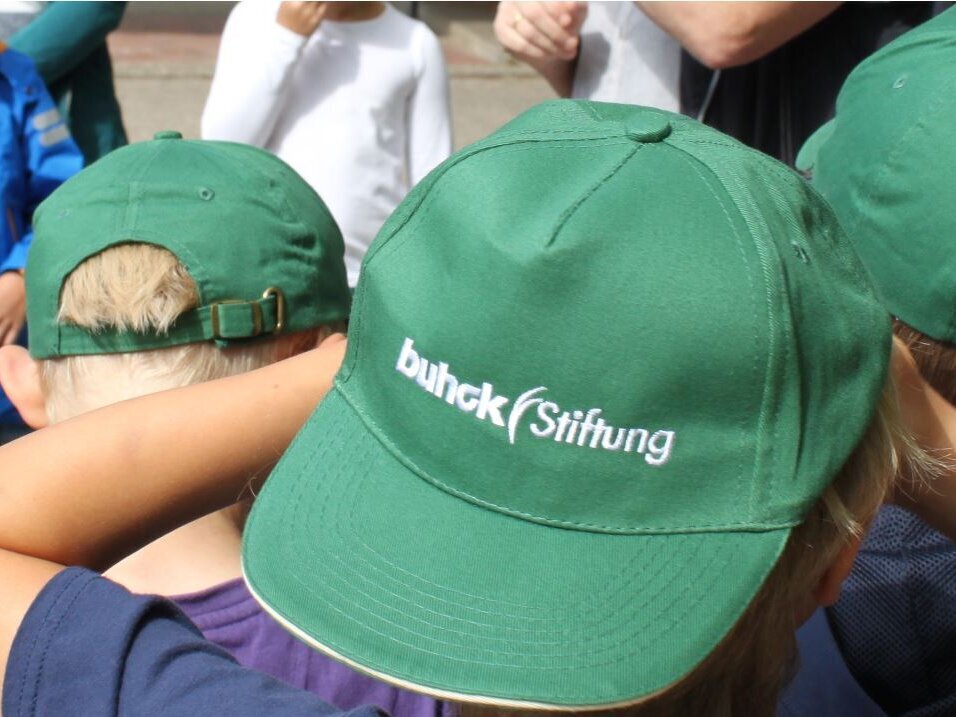 Kind mit grüner Kappe, auf der Buhck Stiftung steht
